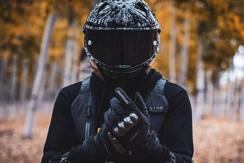 Motorcycle rider wearing a full-face helmet on a tree-lined road